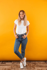 Full length portrait of a smiling young blonde girl - obrazy, fototapety, plakaty