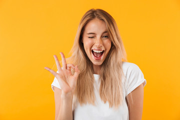 Fototapeta premium Portret szczęśliwa młoda blondynki dziewczyna pokazuje ok gest