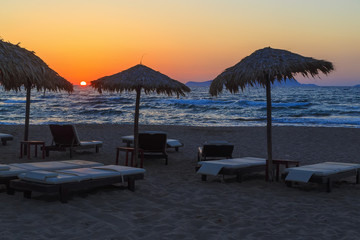 Beach umbrella at sunset, view of chairs and umbrellas on the beach. Sunset at sea. beautiful sky on beach. Wooden beach umbrella