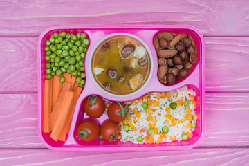 top view of tray with kids lunch for school on pink table