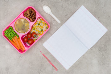 Fototapeta na wymiar top view of tray with kids lunch for school and open notebook on marble table