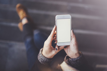 Woman holding hands smartphone and texting message.Female hands using mobile phone.Closeup on blurred background.Flares, bokeh effects. Mock-up.