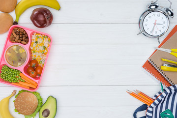 top view of kids lunch for school and alarm clock with bag on wooden table