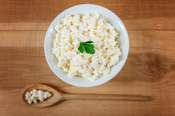 Fresh cottage cheese in a white bowl with spoon