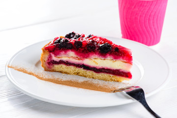 Piece of sweet delicious cherry cheesecake on white plate on whi