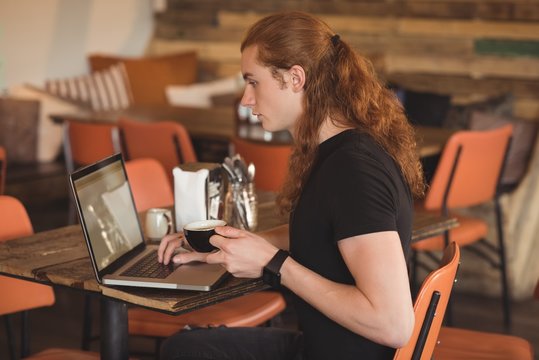 Man using laptop while having coffee