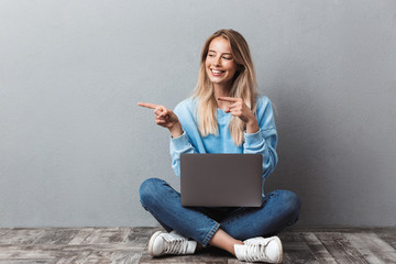 Cheerful young blonde girl using laptop computer