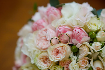 Wedding rings made of metal lie on a beautiful bouquet of fresh flowers. The concept of holidays and ceremonies.