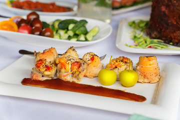Chicken breast rolls with aples and sauce on a white plate on a table.