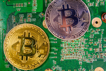 Golden and silver bitcoins on a green circuit board
