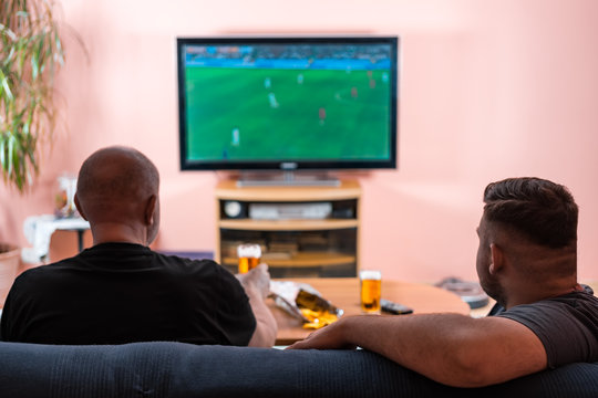 Father and son watching football or soccer on a TV.