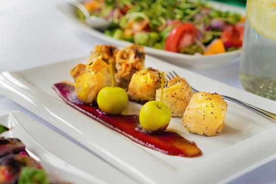 Chicken breast rolls with aples and sauce on a white plate on a table.