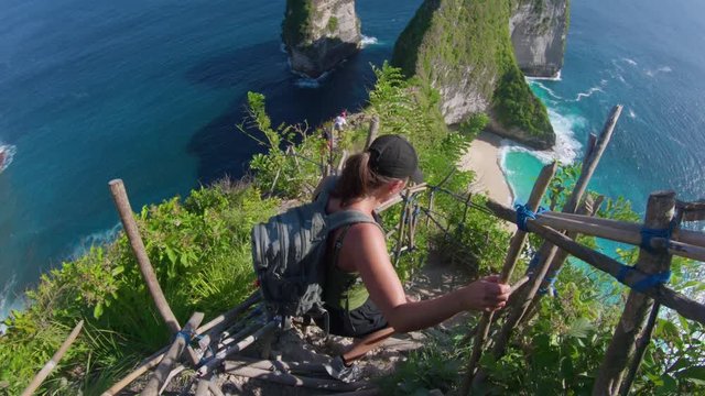 Young woman hikes down steep path to Kelingking beach