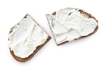 Two half slices of rye bread with cream cheese spread isolated on white from above.
