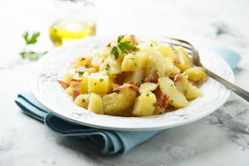 Homemade warm potato salad with onion and fried bacon