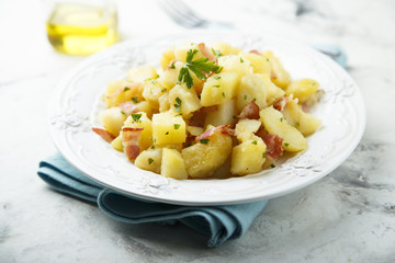 Homemade warm potato salad with onion and fried bacon