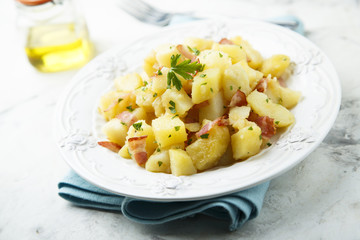 Homemade warm potato salad with onion and fried bacon