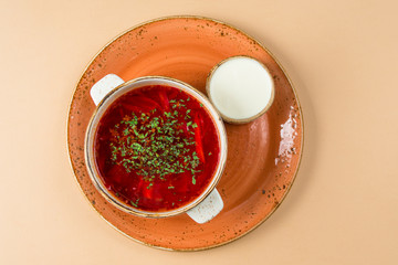 Soup with red borsch and pial with sour cream. Top view on a brown background.
