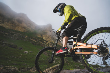 Fototapeta na wymiar Extreme mountain bike sports athlete man in helmet riding outdoors against a background of rocks. Lifestyle. Trial