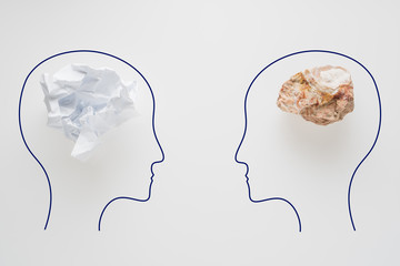 Heads of two people with crumpled paper brain shape and stone brain shape. Two people with...