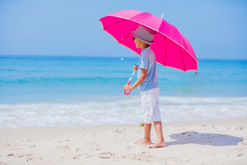 Boy with a pink umbrella on the sandy beach