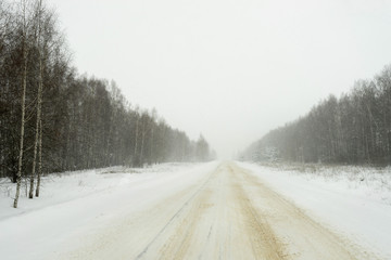 Obraz na płótnie Canvas Vanishing snow-covered straight highway surrounded by winter forest recedes. Nizhegorodsky region, Russia.