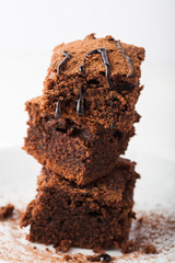 Stack of brownies on white wooden background. Chocolate cake close up. Copy space. 