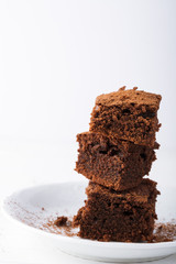 Stack of brownies on white wooden background. Chocolate cake close up. Copy space. 