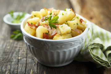 Homemade warm potato salad with onion and fried bacon