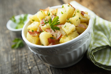 Homemade warm potato salad with onion and fried bacon