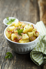 Homemade warm potato salad with onion and fried bacon