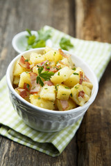 Homemade warm potato salad with onion and fried bacon