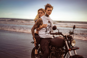 attractive girlfriend hugging boyfriend from back on motorcycle on ocean beach