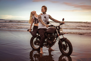 Obraz premium girlfriend touching boyfriend and sitting on motorcycle on ocean beach