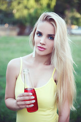 Young woman holding bottle with juice outdoor