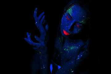 A girl with blue skin and cosmetic make-up, made of neon and fluorescent paints. The concept of star space in a person. Magic fantasy and dreams.