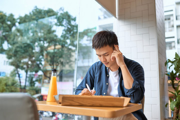 Skilled handsome male chief editor reading script review of young author correcting mistakes in...