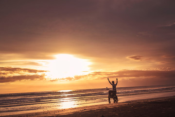 biker standing near motorbike with hands up and looking at beautiful sunrise
