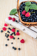 A basket with blueberries and raspberries on wooden background