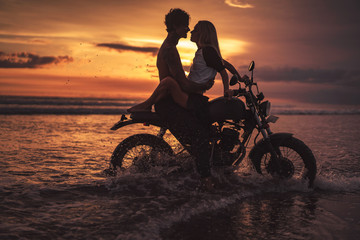 Plakat passionate couple hugging on motorbike at beach during sunset