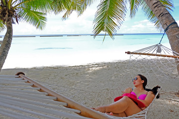 Beautiful woman with hat sleep on the hanging swing on the beach. Maldive.