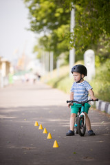 Cute little toddler boy riding his balance bike in the park on a sunny summer day,