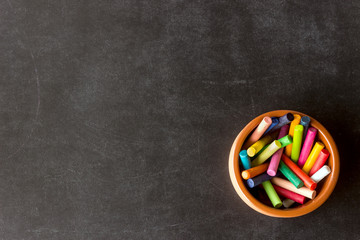 Bright pastel crayons lie in a ceramic bowl on a black school board. Children's creativity....