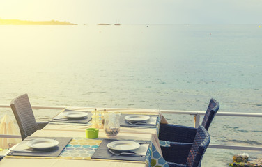 Wooden table and chairs of a street cafe on the background of the sea on a sunny summer day