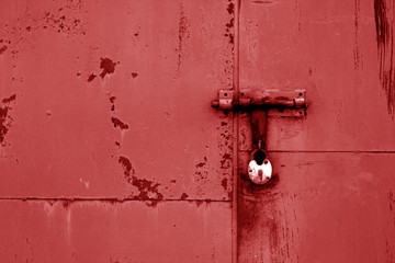 Old padlock on metal gate in red color.