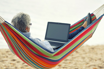 mit Laptop in der Hängematte am See