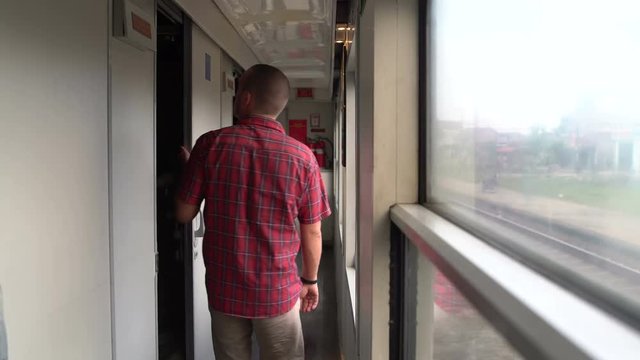 A man exits the train compartment and goes to the vestibule
