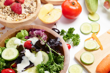 Close up of mixed vegetables salad, muesli and fresh fruits on white background.