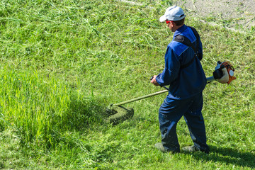 man cuts grass with lawn mower