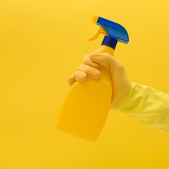 Hand in yellow rubber glove with cleaning product